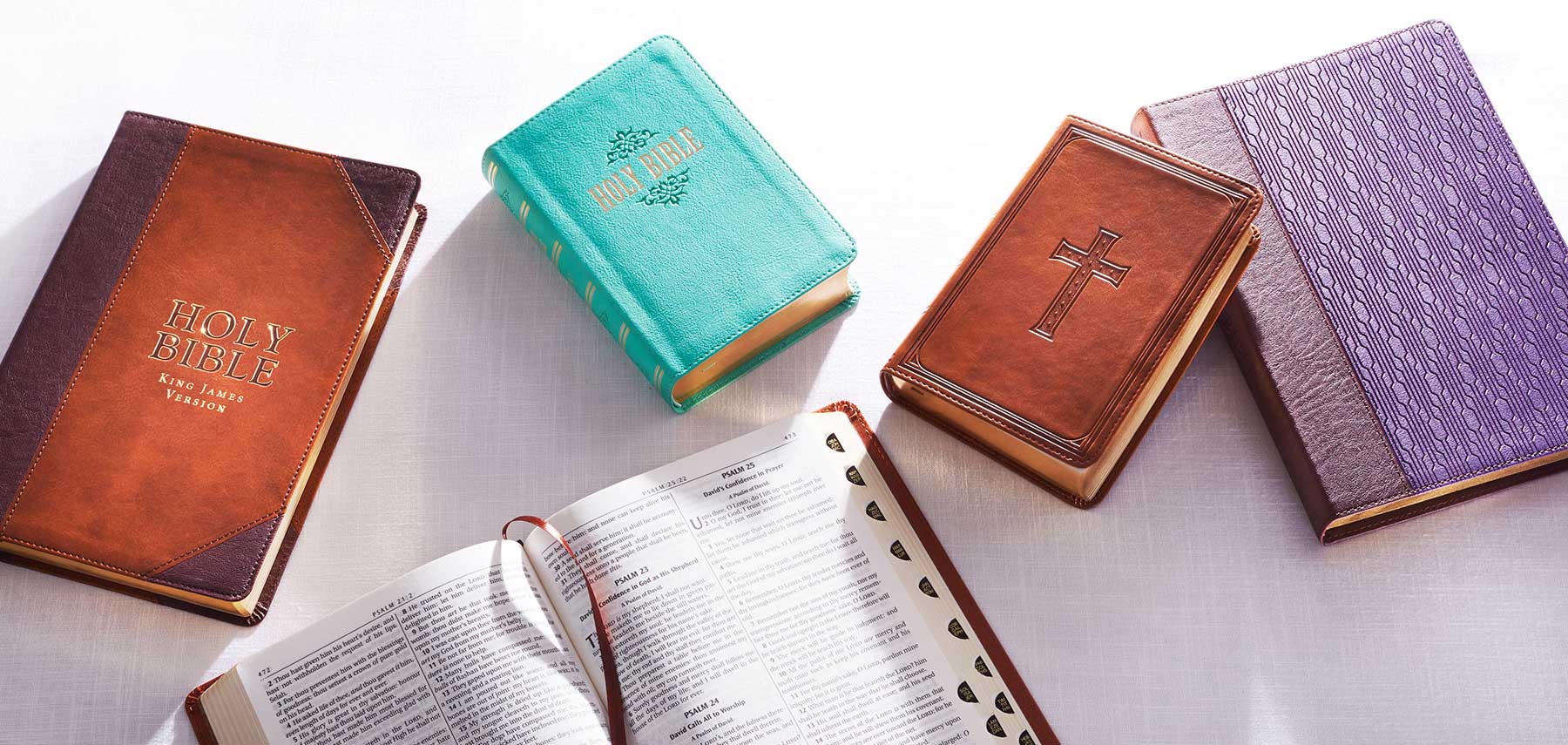 Brown, teal, purple bibles with open Bible and ribbon market and compact brown Bible with a debossed cross